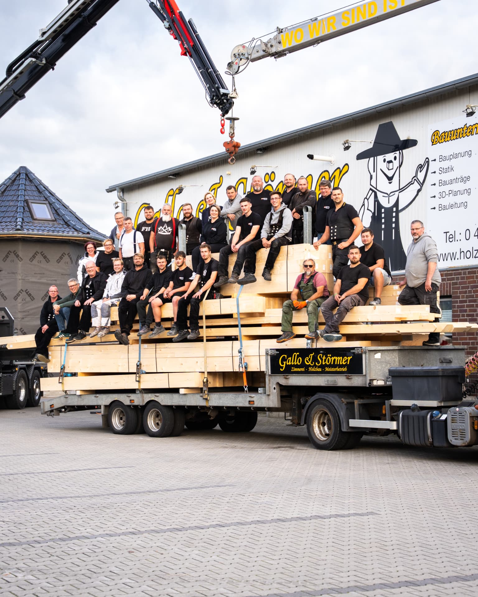 Das Team von Gallo & Störmer vor dem firmeneigenen Lkw mit Kran und beladenen Holzbalken