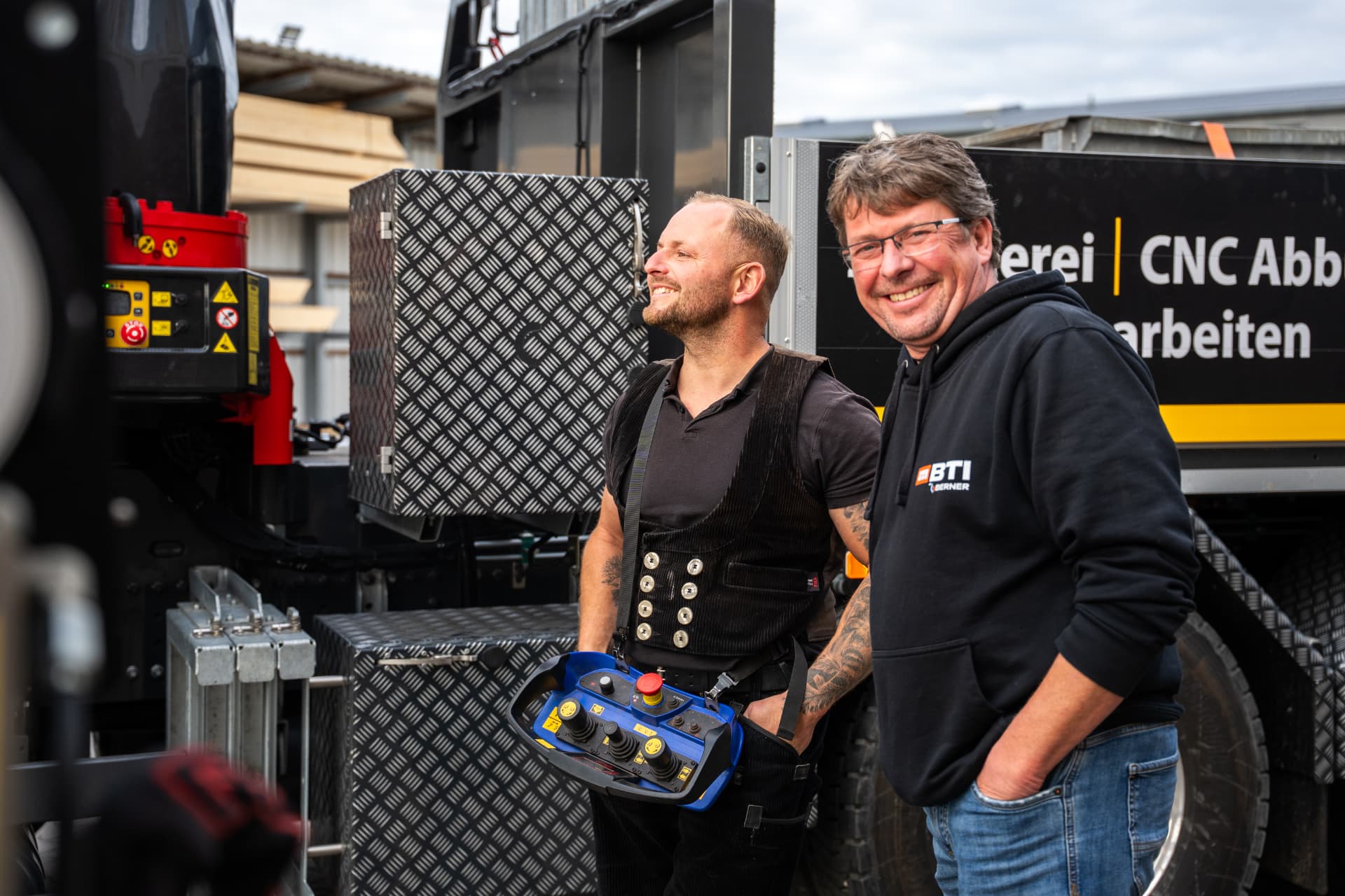 Zwei Männer von Gallo & Störmer stehen vor dem firmeneigenen Lkw mit Kran auf dem Betriebsgelände